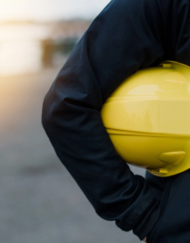 un homme portant un casque de travaux sous son bras